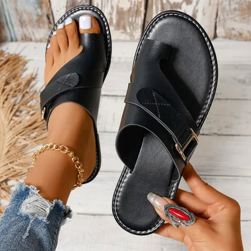 Black toe-loop slides showing layered straps and white contrast stitching at the sole edge.