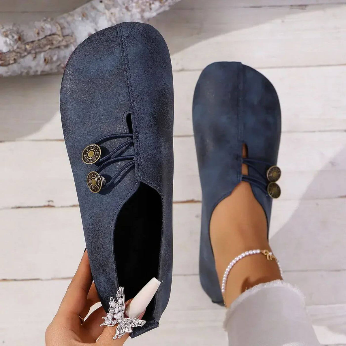 Top view of navy blue shoes with decorative cords and metal details.