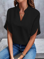 Black blouse with curved sleeve panels, worn with jeans.