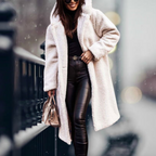 Creamy white long coat worn open over a black outfit.