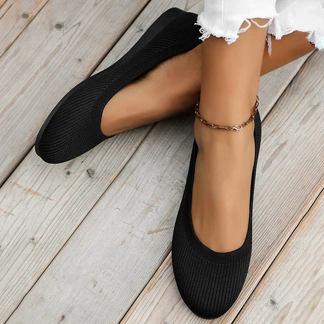 Black ballet flats worn with light-coloured trousers.