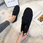Black plush loafer-style slippers with closed backs and broad front bands.