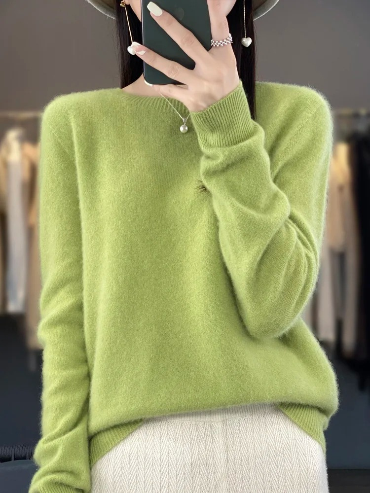 Light green long-sleeve jumper worn with pale trousers.