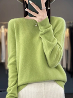 Light green long-sleeve jumper worn with pale trousers.