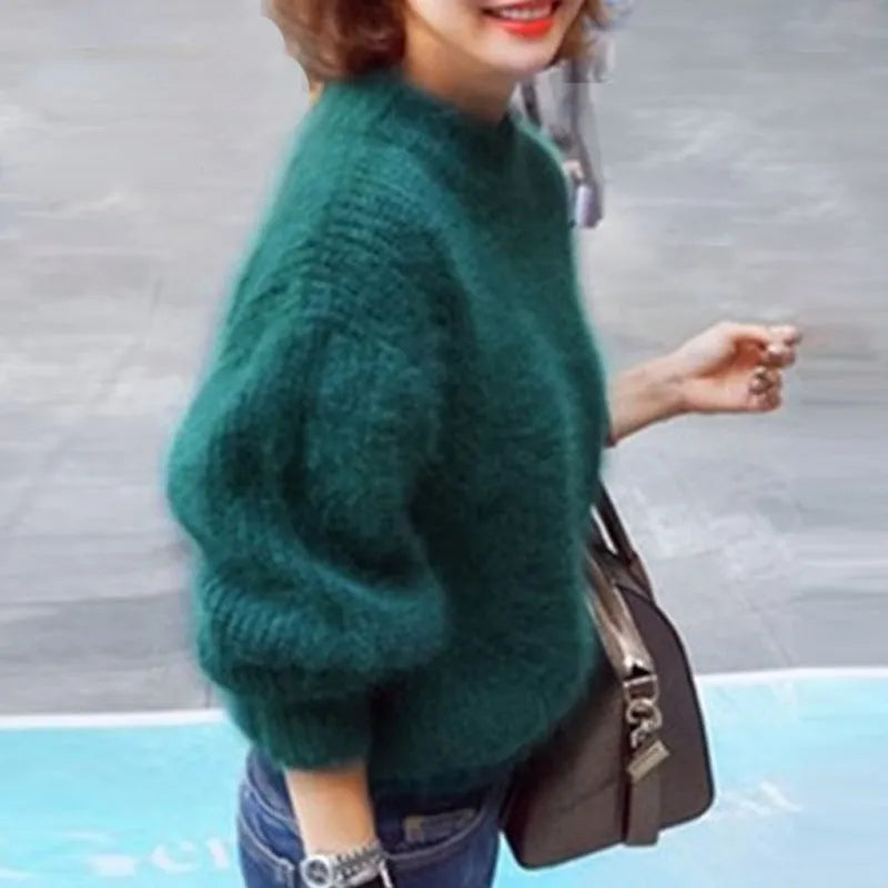 Woman wearing a green fuzzy jumper with full sleeves and ribbed cuffs.