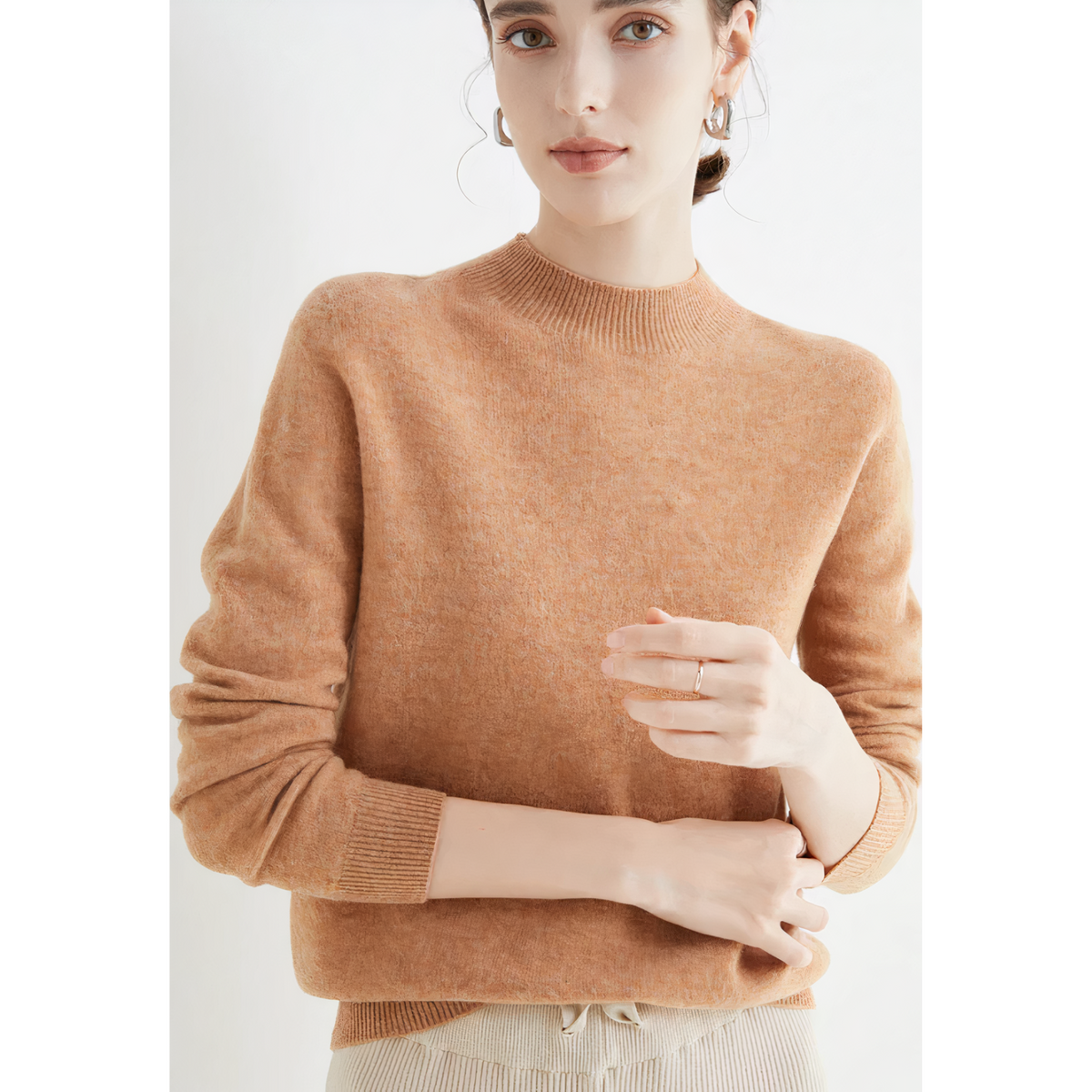 Warm tan-gold jumper showing ribbed cuffs.