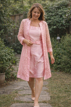 Pink knee-length dress worn with a matching lace-effect jacket.