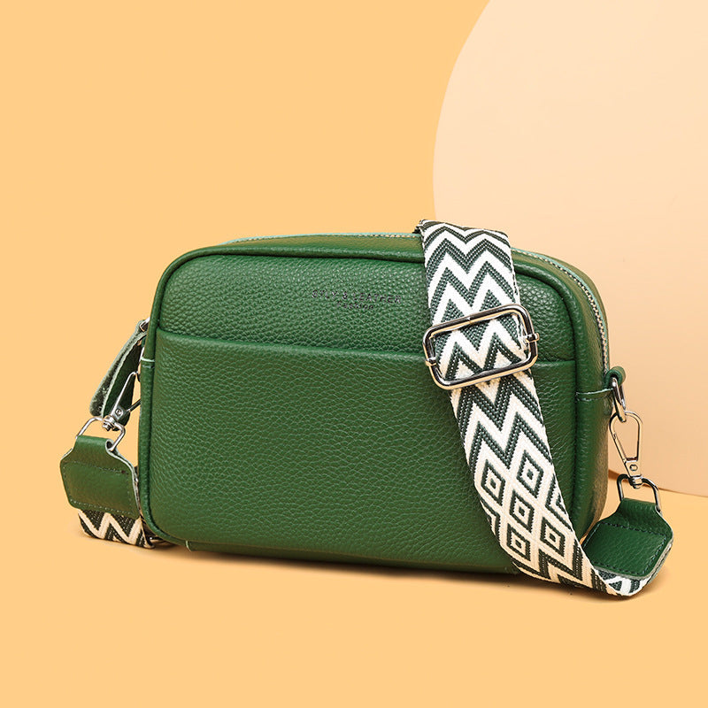 Green bag with a patterned adjustable strap on a yellow background.