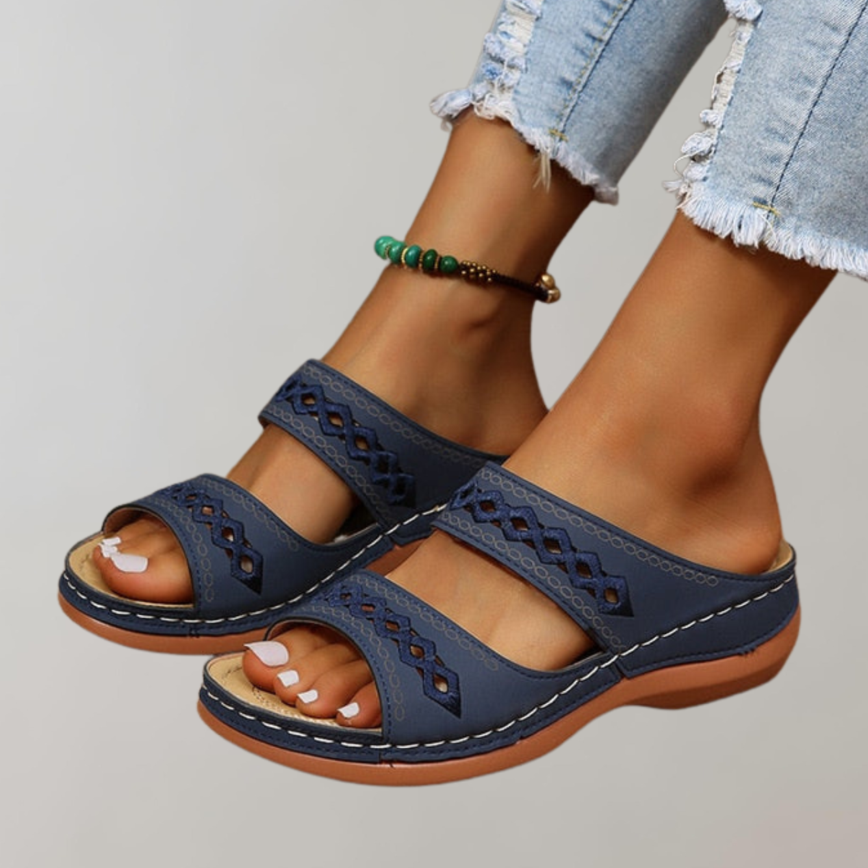 Dark-blue slide sandals worn with cropped jeans.