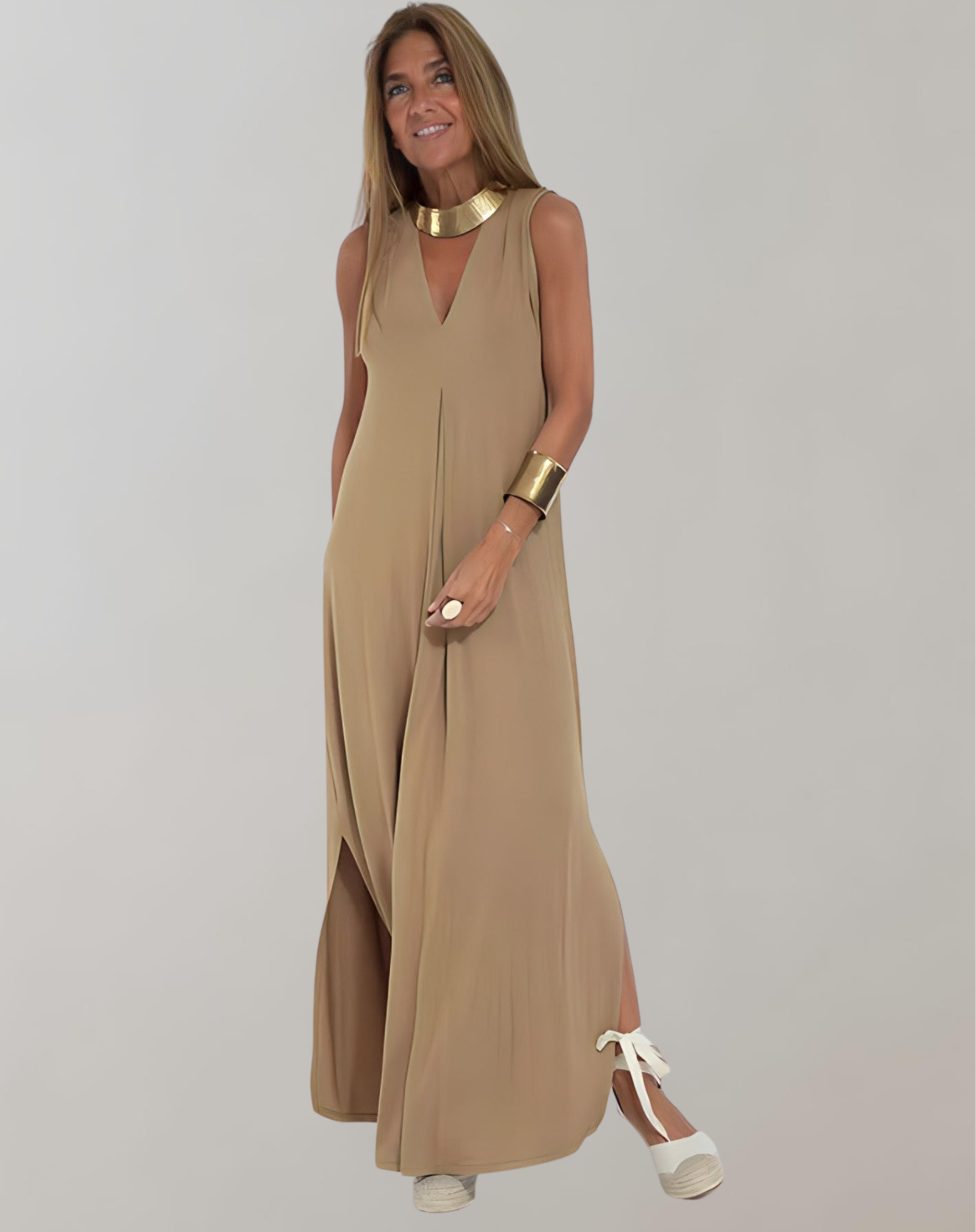 Tan sleeveless maxi dress with a V neckline and loose drape, worn with white sandals.