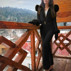 Black winter jumpsuit with a high collar and matching waist belt, worn with mittens.