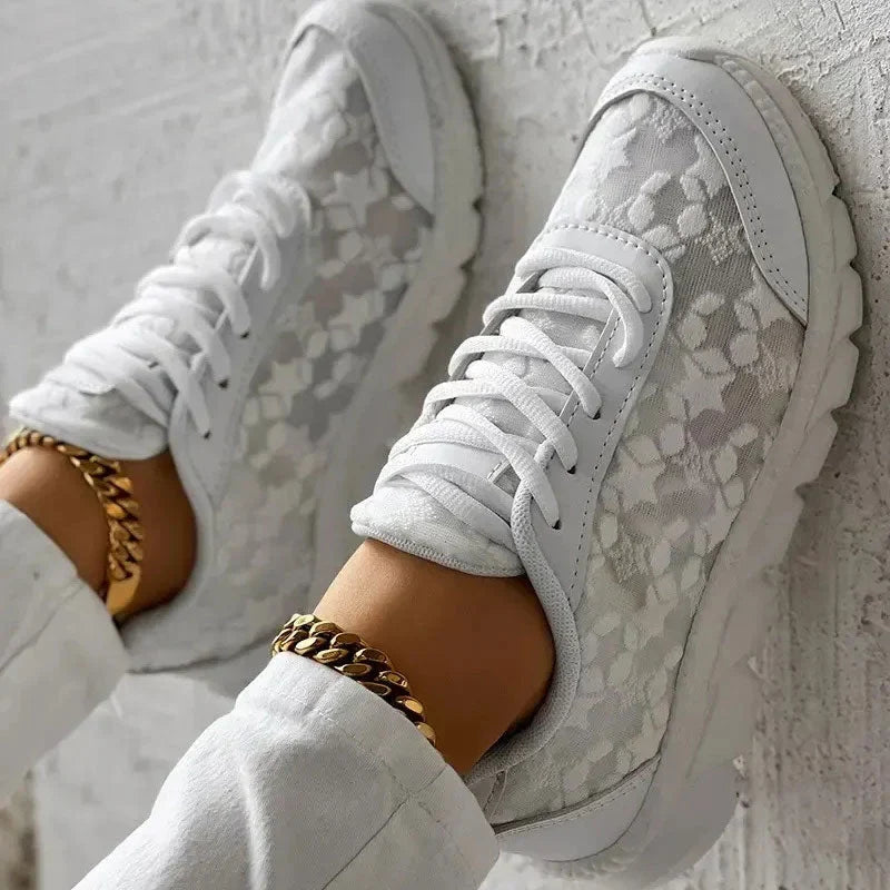 White trainers viewed from above, showing floral panels and front laces.