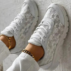 White trainers viewed from above, showing floral panels and front laces.