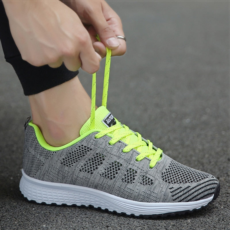 Grey trainer with bright green laces being tied.