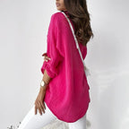 Rear side view of a bright pink blouse with a rounded hem.