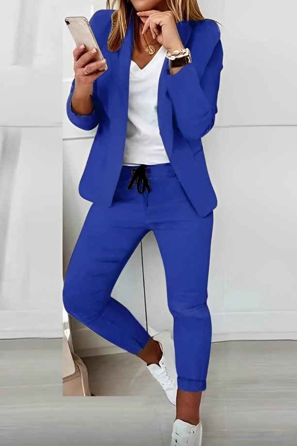 Blue open-front blazer and drawstring trousers shown with a contrasting top and white trainers.