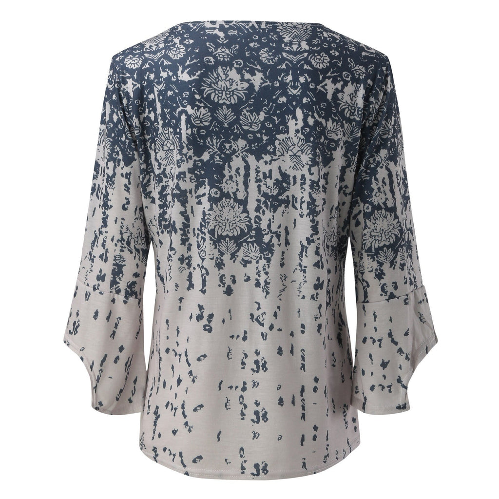 Back view of a pale blouse with a blue floral print and flared sleeves.
