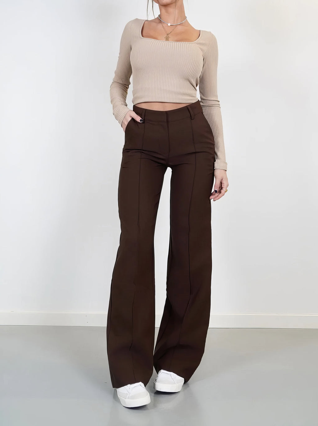 Brown trousers worn to show the high waist and pocket openings.
