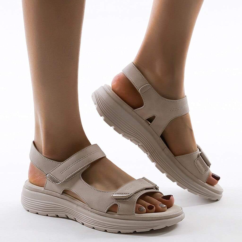 Pale beige sandals viewed from the side with adjustable straps and open heels.