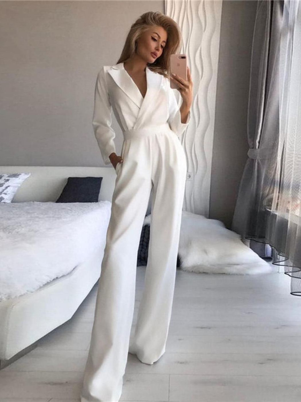 White jumpsuit with a shaped waist, worn beside a sofa.