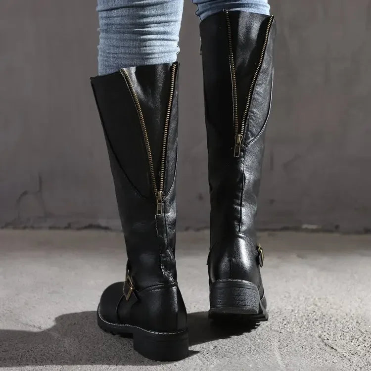 Rear view of black tall boots with open zip details along the shafts.