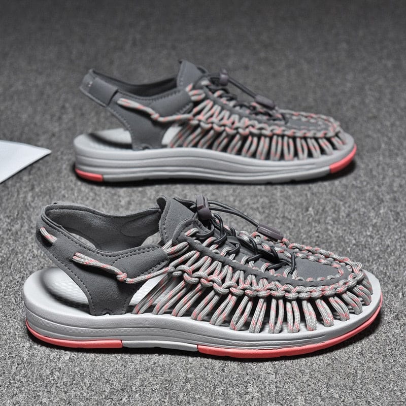 Pair of grey and pink cord sandals on a dark surface.