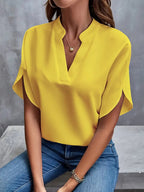 Yellow blouse with curved overlapping sleeve edges.