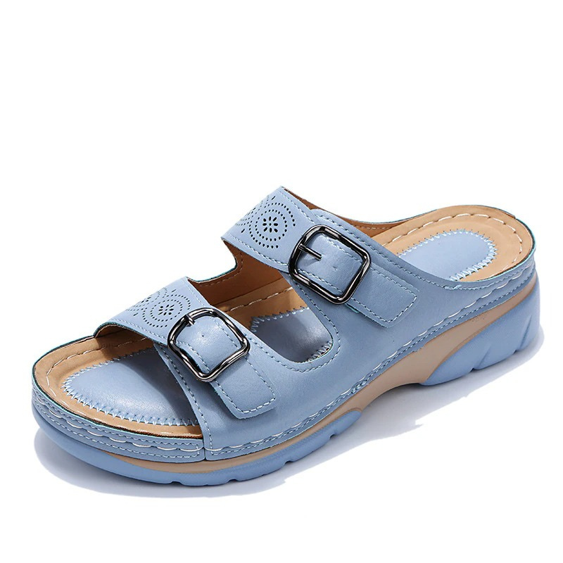 Light blue slide sandal with two metal buckles and circular strap cutouts.