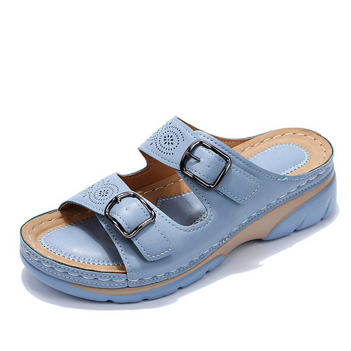 Light blue slide sandal with two metal buckles and circular strap cutouts.