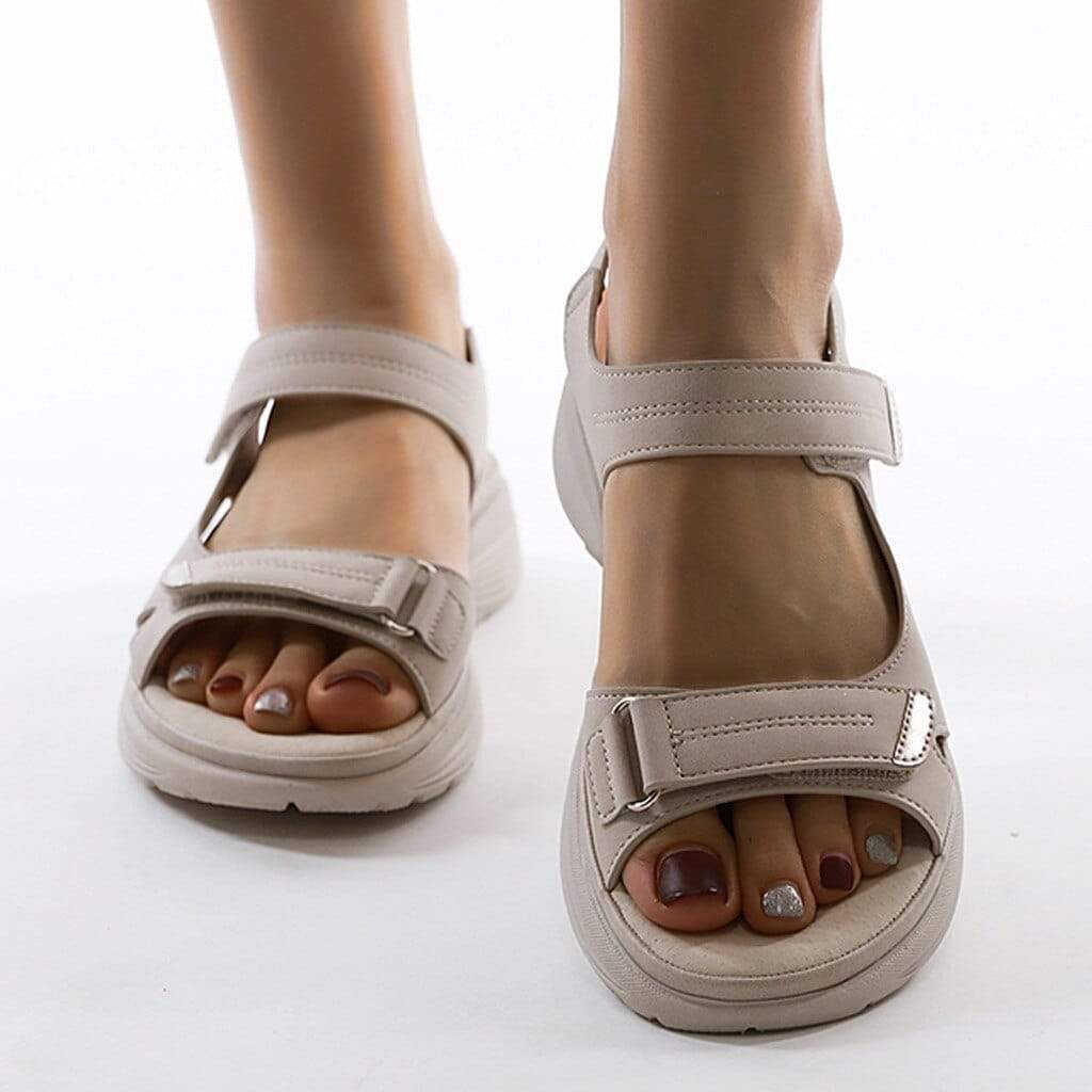 Pale beige sandals shown from the front with adjustable straps and open toes.