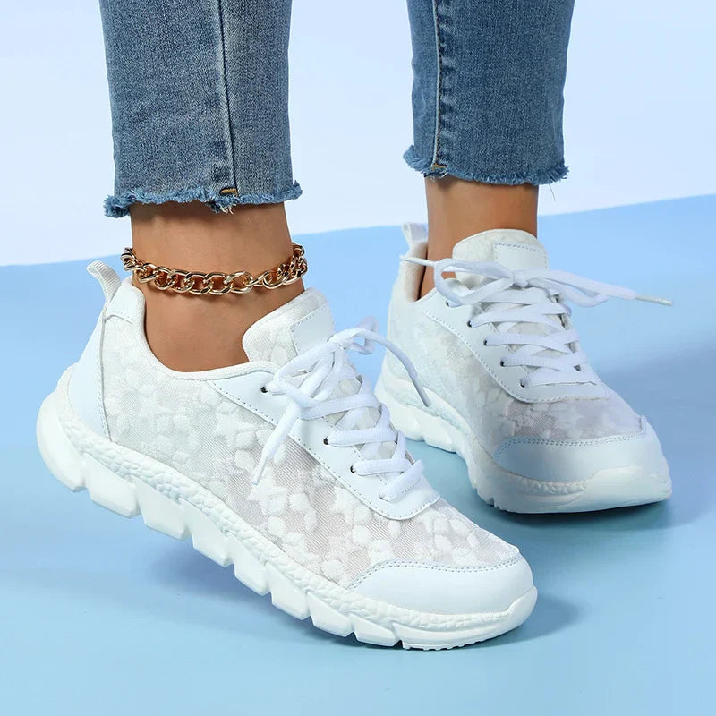 Front and side view of white floral trainers worn with jeans.