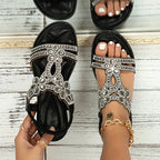 Black sandals with flower-shaped uppers and shiny edging.