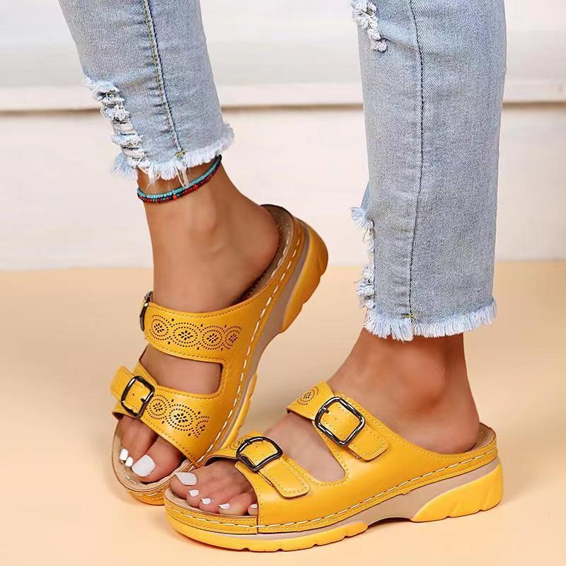 Yellow slide sandals with circular cutouts and adjustable buckles shown on feet.