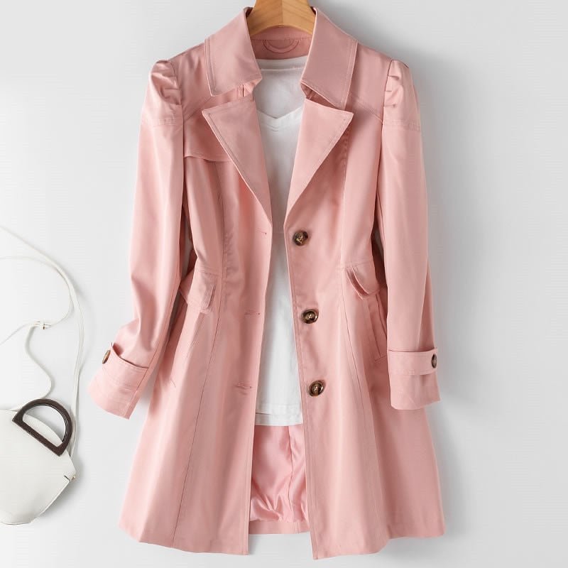 Pink trench-style jacket with broad lapels and buttoned cuffs, displayed on a wooden hanger.