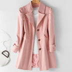 Pink trench-style jacket with broad lapels and buttoned cuffs, displayed on a wooden hanger.