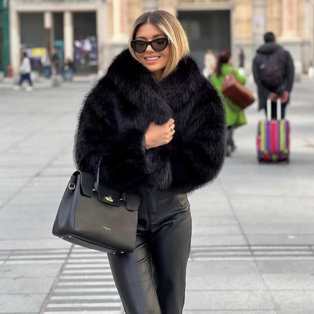 Black shaggy jacket with a wide collar, worn outdoors with dark trousers.
