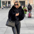 Black shaggy jacket with a wide collar, worn outdoors with dark trousers.