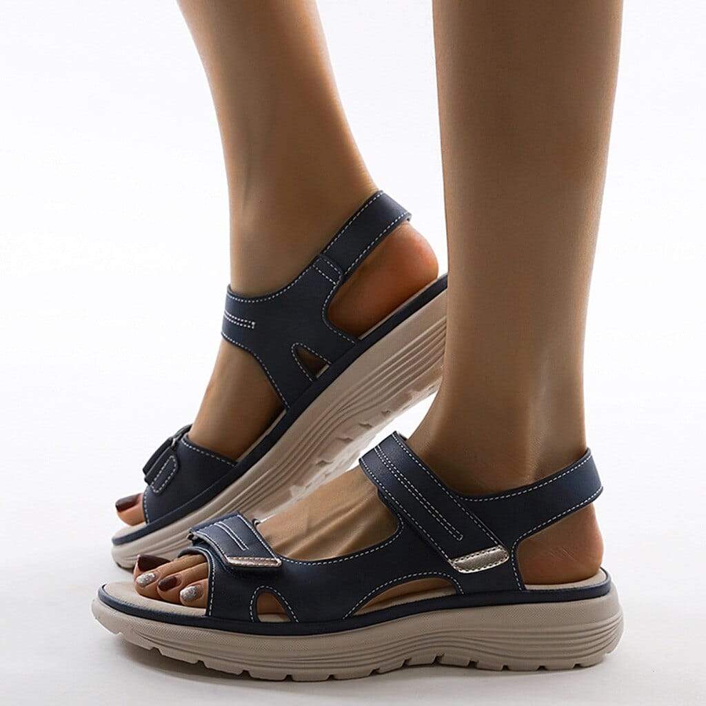 Side view of dark blue sandals showing strap stitching and grooved soles.
