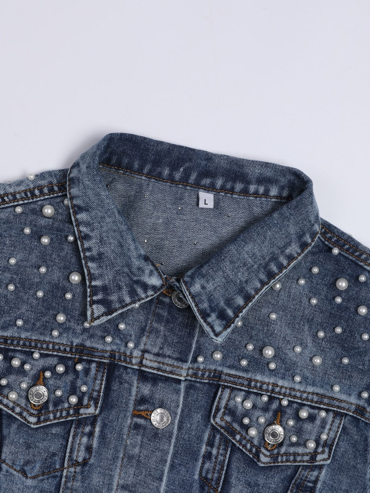 Close view of the collar and beaded chest pockets on a blue denim jacket.