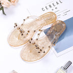 Gold-tone sandals with transparent studded straps and decorative bows.