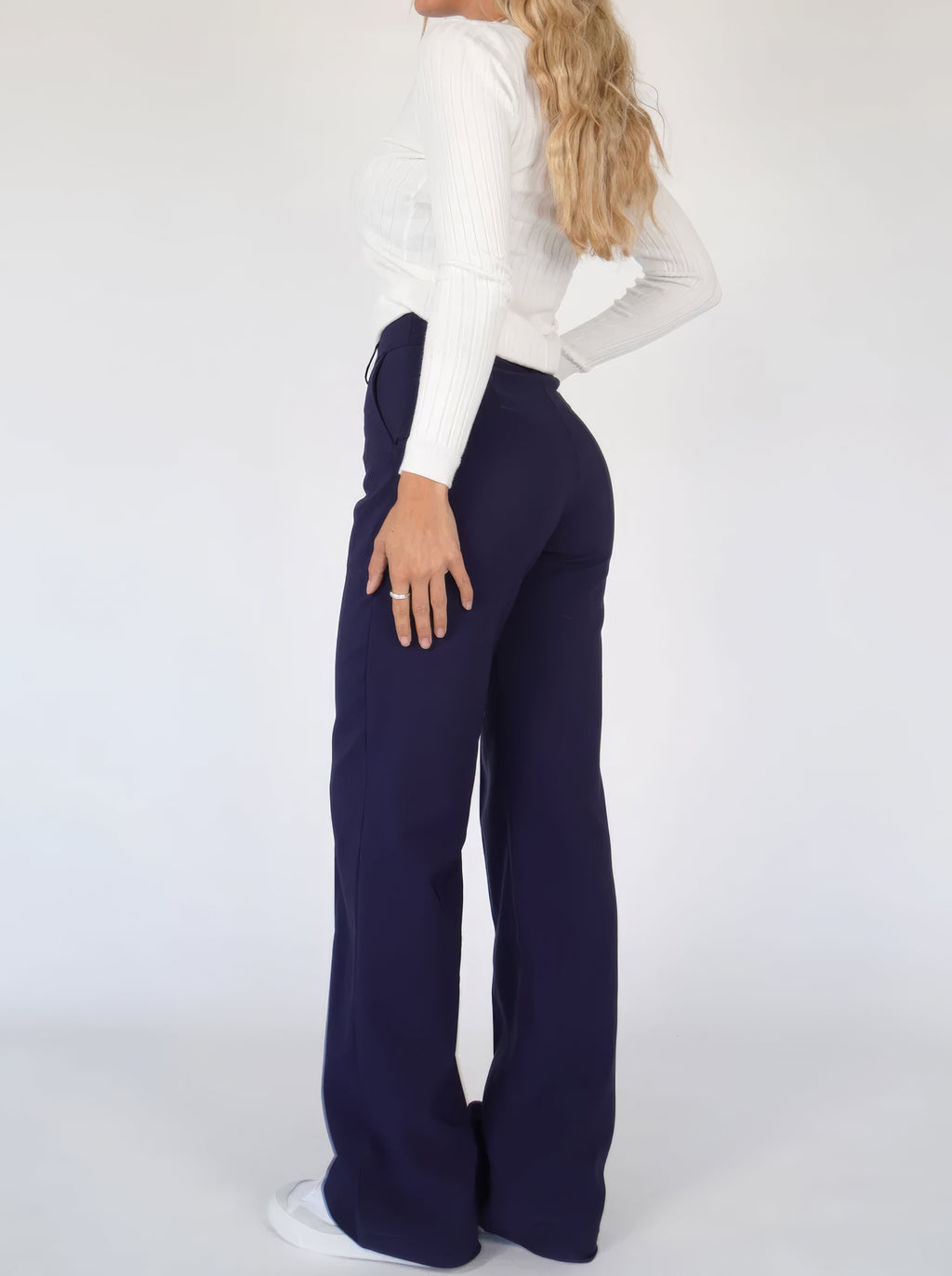 Rear side view of dark blue full-length trousers.