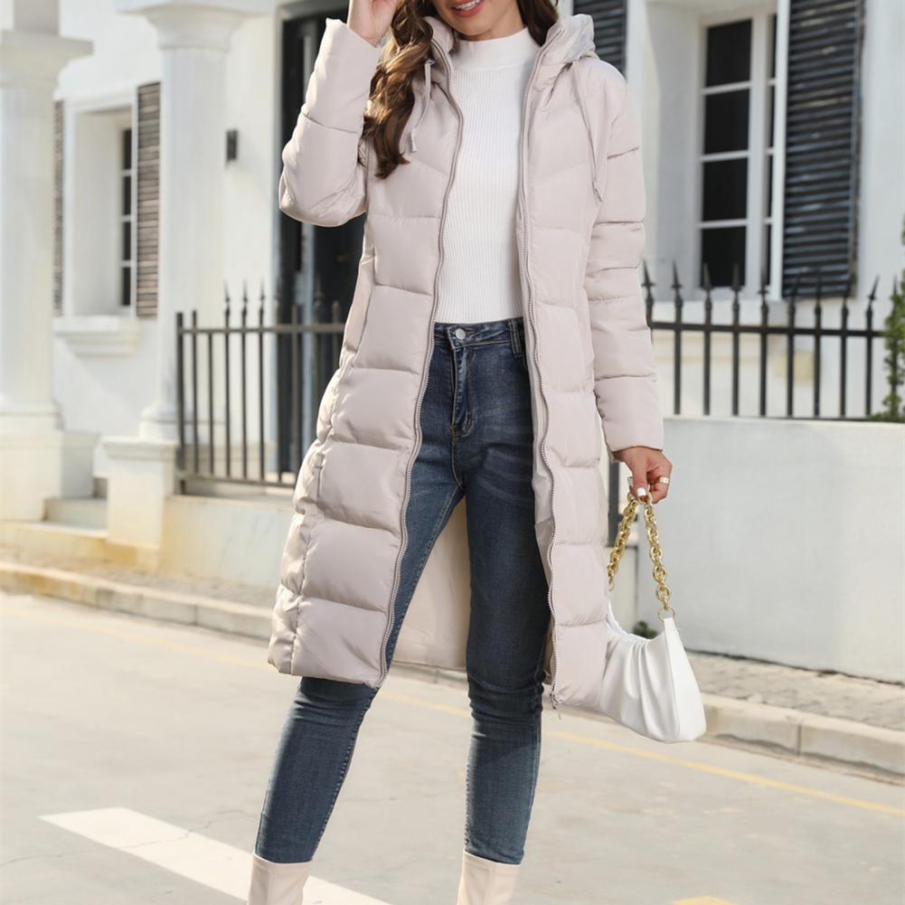 Beige long quilted coat worn open, with a hood, front zip and outside pockets.