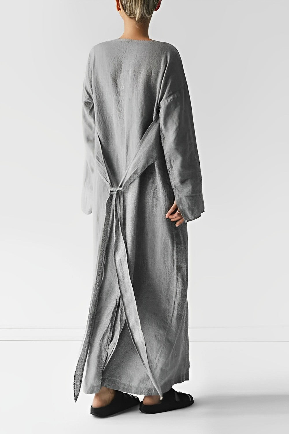 Rear view of a long grey dress with fabric panels tied behind the waist.