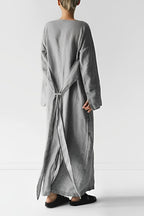 Rear view of a long grey dress with fabric panels tied behind the waist.