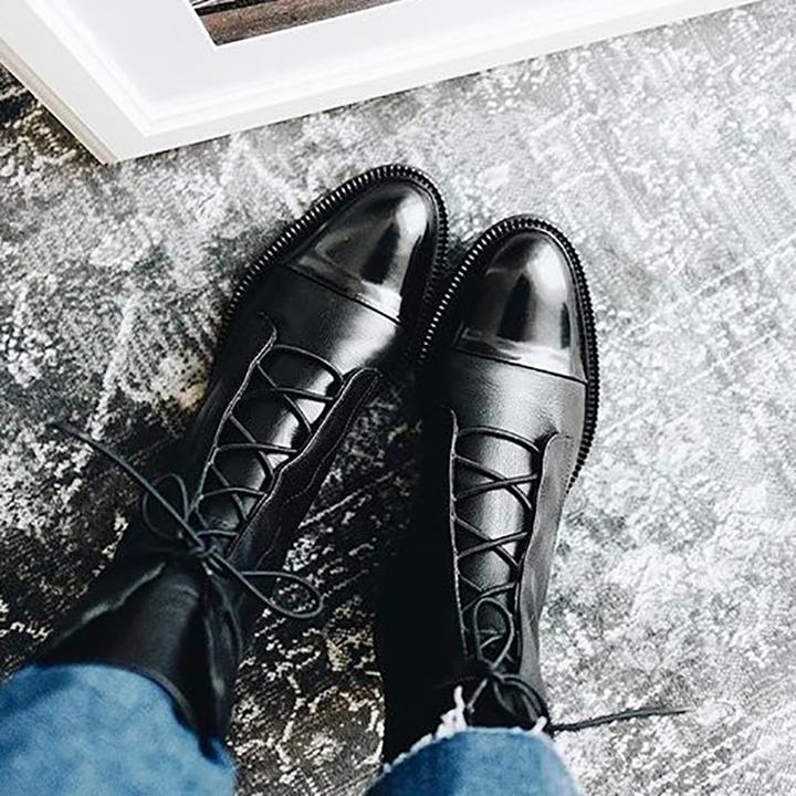 Black lace-up boots viewed from above on a grey floor.