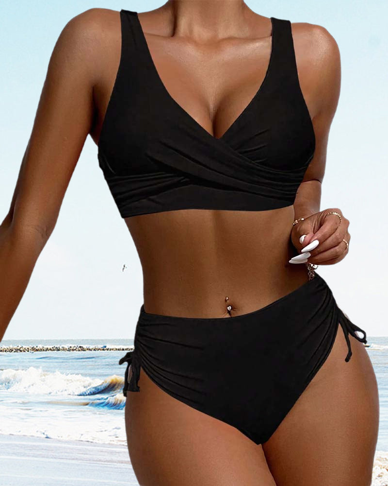 Black crossover bikini top and matching briefs beside the sea.