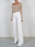 White full-length trousers worn with a beige top.