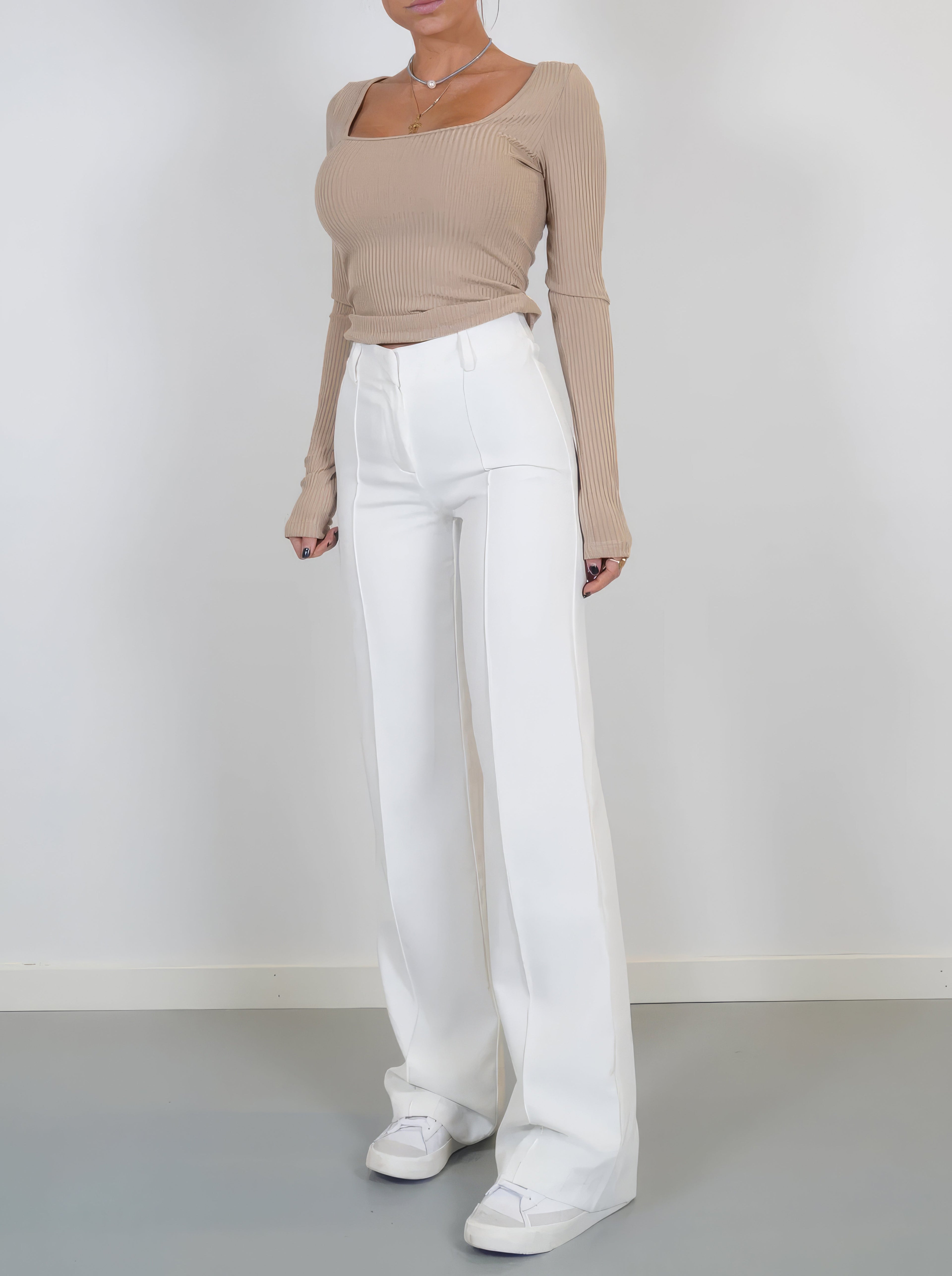 White full-length trousers worn with a beige top.