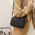 Black shoulder bag worn with a tan blazer.