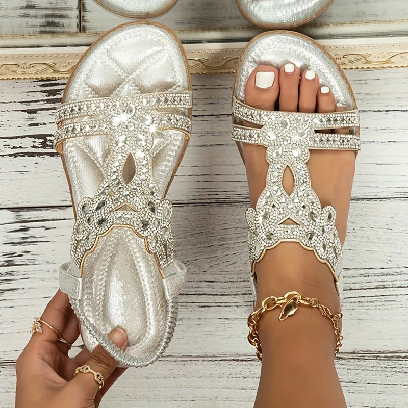 Silver-coloured open-toe sandal with floral trim and a heel strap.